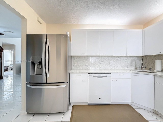 kitchen with sink, light tile patterned floors, stainless steel refrigerator with ice dispenser, white dishwasher, and white cabinets