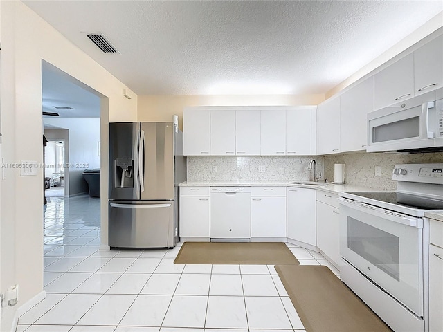 kitchen with sink, light tile patterned floors, white appliances, decorative backsplash, and white cabinets