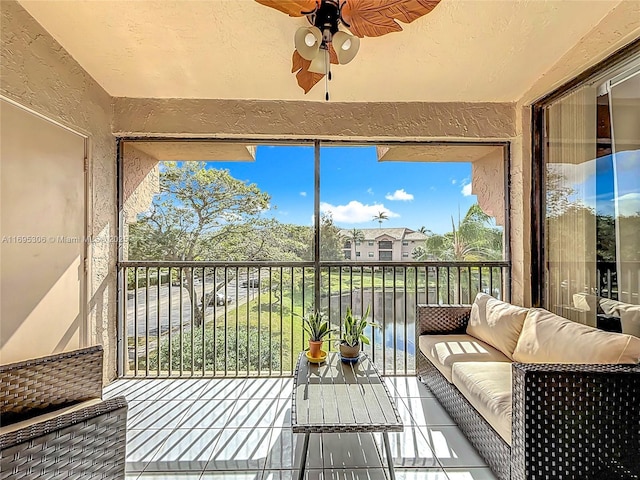 sunroom featuring ceiling fan and a water view