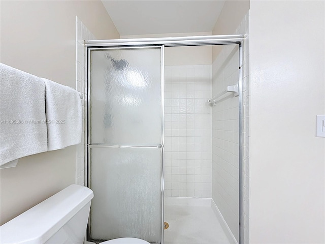 bathroom featuring a shower with door and toilet