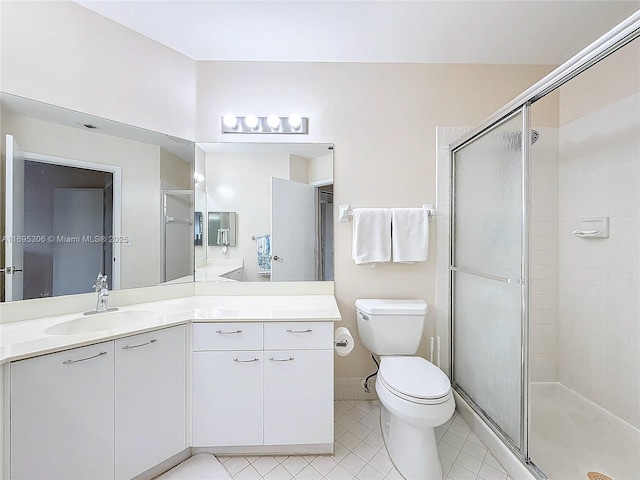 bathroom with tile patterned floors, vanity, toilet, and a shower with door