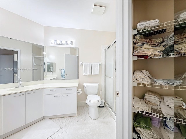 bathroom with vanity, toilet, an enclosed shower, and tile patterned flooring