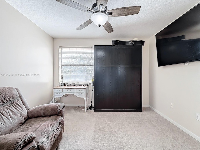 sitting room with ceiling fan, light colored carpet, and a textured ceiling