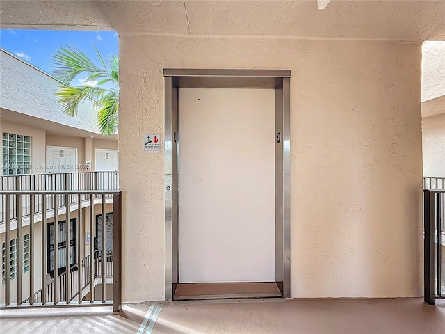 view of exterior entry with elevator and a balcony