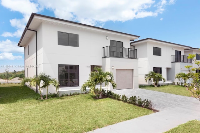 contemporary home with a front yard, a balcony, and a garage