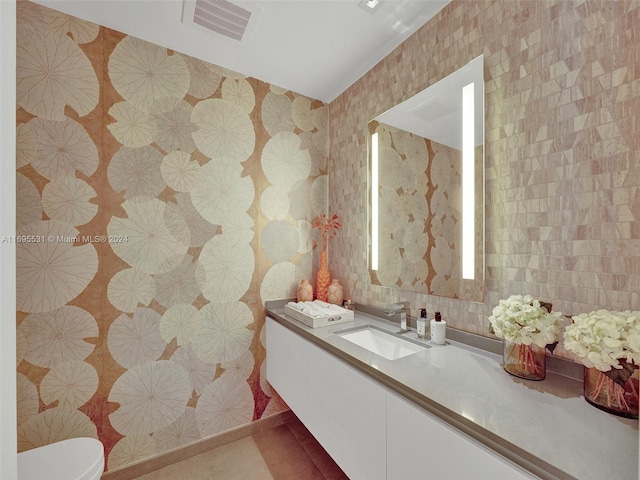 bathroom with tile patterned flooring, vanity, toilet, and tile walls