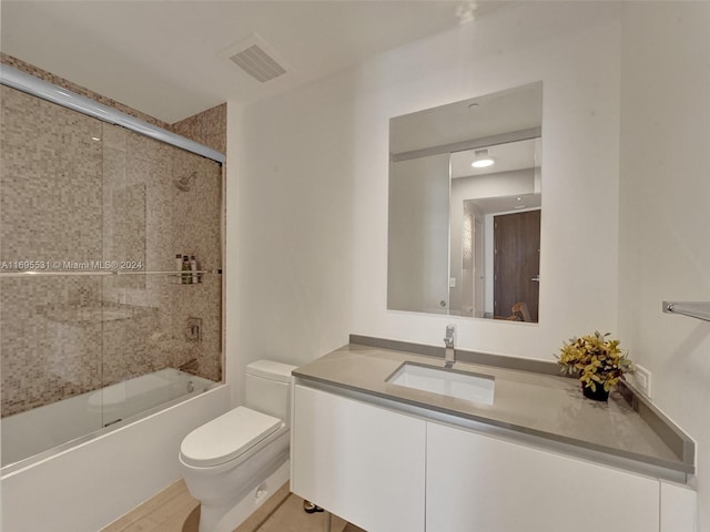 full bathroom featuring vanity, hardwood / wood-style flooring, toilet, and enclosed tub / shower combo