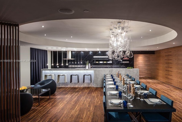 dining room with wood-type flooring, wooden walls, and a chandelier