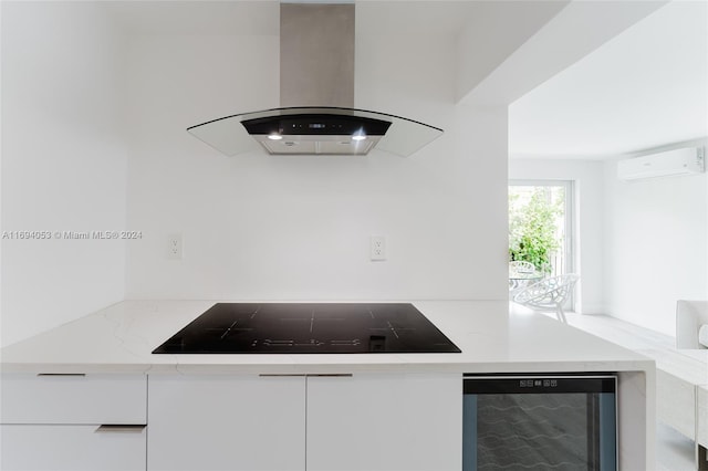 kitchen with island exhaust hood, wine cooler, black electric cooktop, an AC wall unit, and white cabinetry