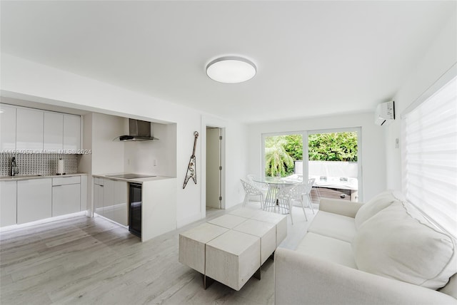 living room with light hardwood / wood-style floors, a wall unit AC, and sink