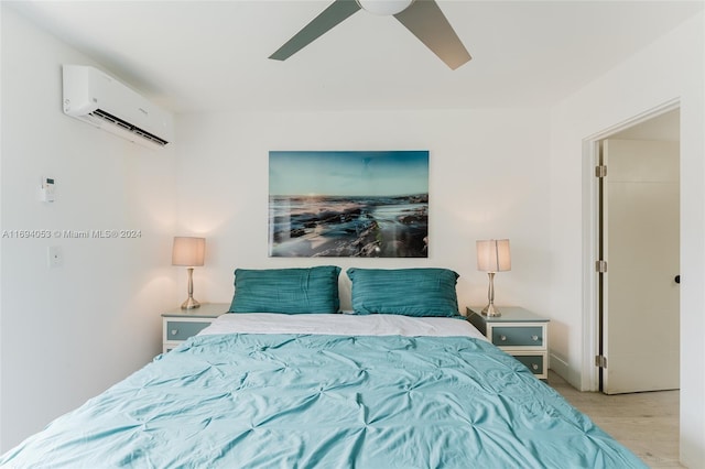 bedroom with a wall unit AC, ceiling fan, and light hardwood / wood-style floors