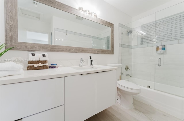 full bathroom with shower / bath combination with glass door, toilet, vanity, and hardwood / wood-style flooring