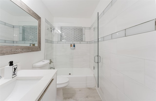 full bathroom with vanity, toilet, wood-type flooring, and bath / shower combo with glass door