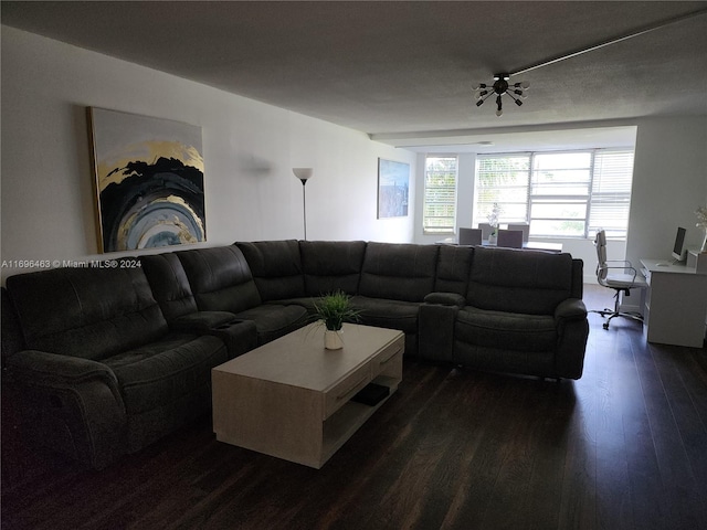 living room with a textured ceiling and dark wood-type flooring