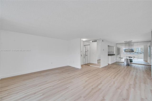 unfurnished living room featuring light wood-type flooring and a textured ceiling