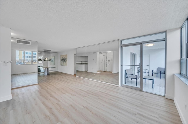 unfurnished living room with light hardwood / wood-style flooring and a textured ceiling