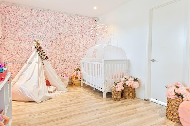 bedroom featuring wood-type flooring and a nursery area