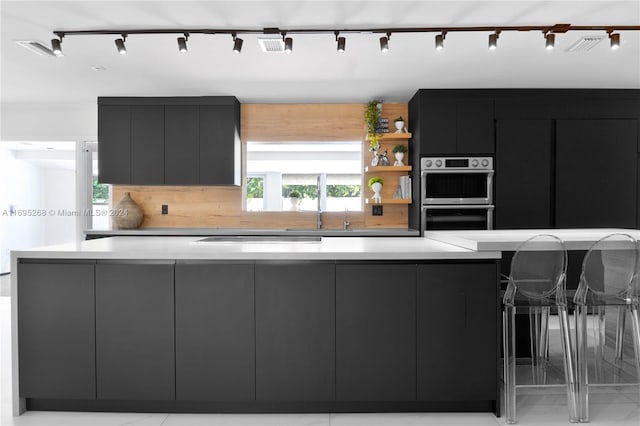 kitchen with a breakfast bar area, backsplash, sink, and appliances with stainless steel finishes