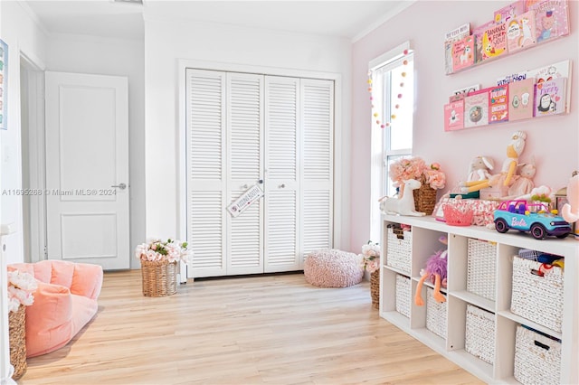 game room with light wood-type flooring and crown molding