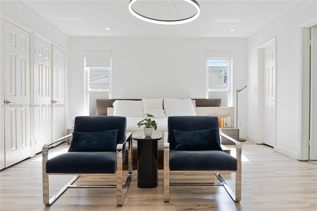 living area with light hardwood / wood-style floors and crown molding