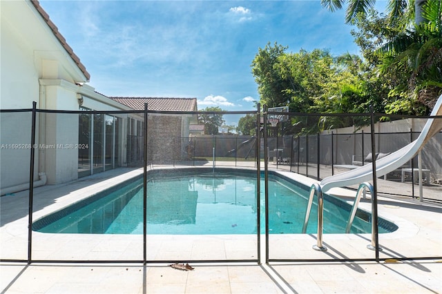 view of pool featuring a water slide and a patio