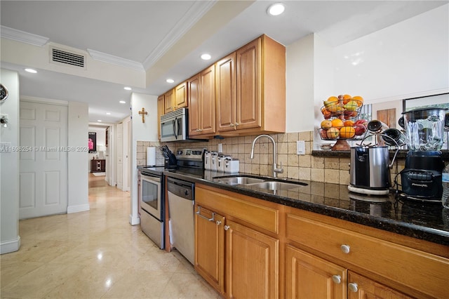 kitchen featuring sink, stainless steel appliances, tasteful backsplash, dark stone counters, and ornamental molding