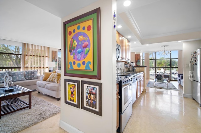 kitchen with ornamental molding, stainless steel appliances, a wealth of natural light, and an inviting chandelier