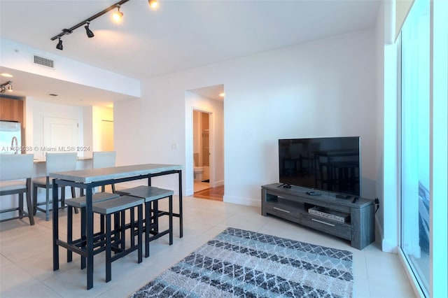 dining space with light tile patterned flooring and rail lighting