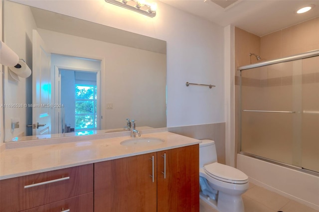 full bathroom with toilet, vanity, tile patterned floors, and bath / shower combo with glass door