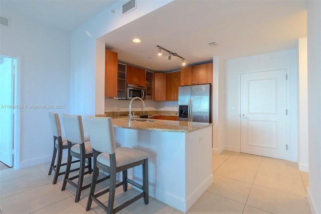 1945 S Ocean Dr Unit M5, Hallandale Beach, FL 33009 - kitchen featuring appliances with stainless steel finishes, brown cabinetry, a sink, light stone counters, and baseboards