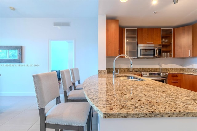1945 S Ocean Dr Unit M5, Hallandale Beach, FL 33009 - kitchen featuring appliances with stainless steel finishes, brown cabinetry, a sink, and light stone countertops