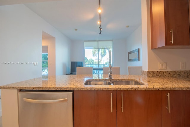 kitchen with stainless steel dishwasher, light stone countertops, sink, and track lighting