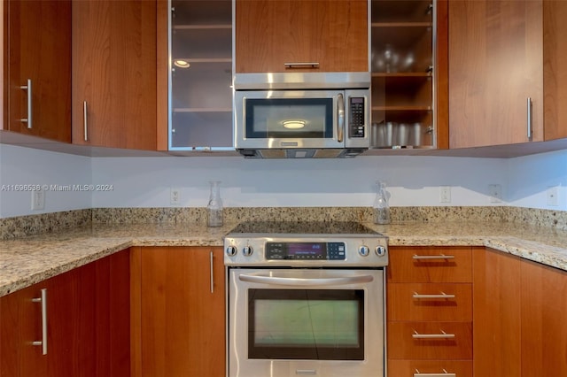 1945 S Ocean Dr Unit M5, Hallandale Beach, FL 33009 - kitchen featuring appliances with stainless steel finishes, brown cabinetry, glass insert cabinets, and modern cabinets