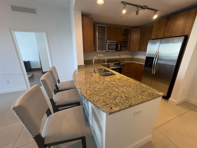 kitchen with sink, stainless steel appliances, kitchen peninsula, a breakfast bar, and light tile patterned flooring