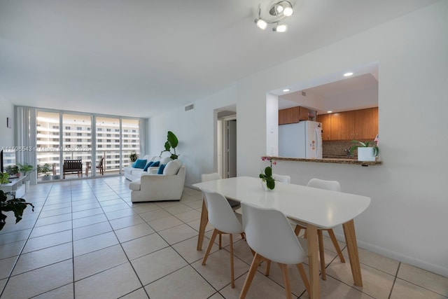 dining space featuring light tile patterned floors, visible vents, floor to ceiling windows, and baseboards