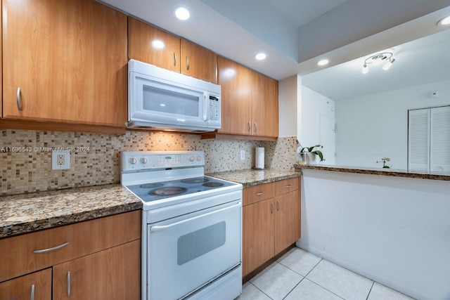 kitchen with decorative backsplash, stone counters, white appliances, and light tile patterned floors