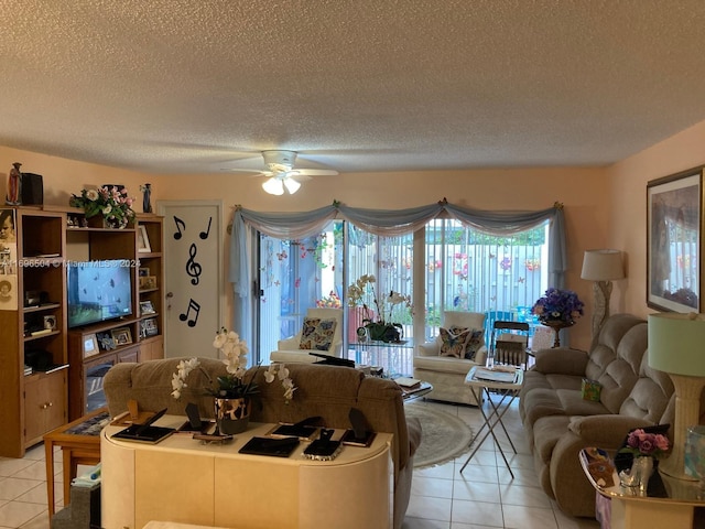 living room with ceiling fan, light tile patterned floors, and a textured ceiling