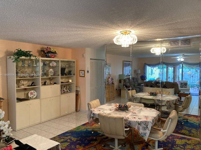 dining room with ceiling fan with notable chandelier, light tile patterned floors, and a textured ceiling