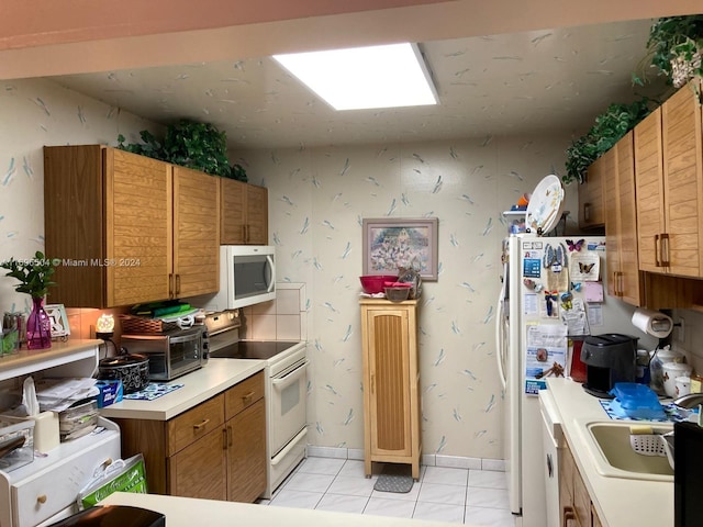 kitchen with sink, light tile patterned floors, and white appliances