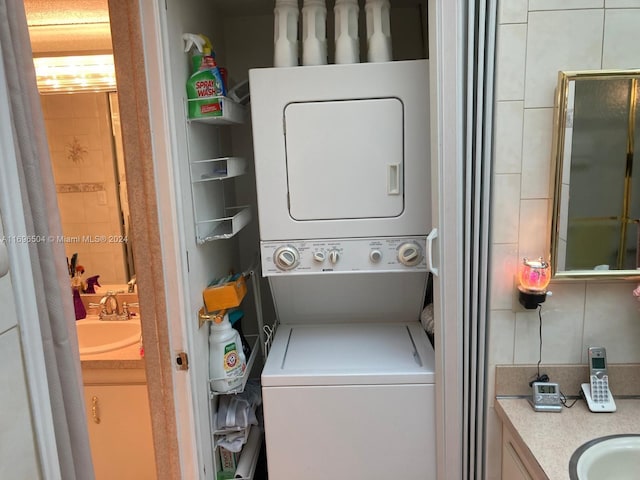 laundry area with stacked washer / drying machine and sink