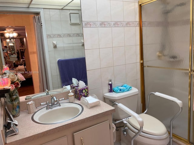 bathroom featuring a shower with door, vanity, tile walls, and toilet