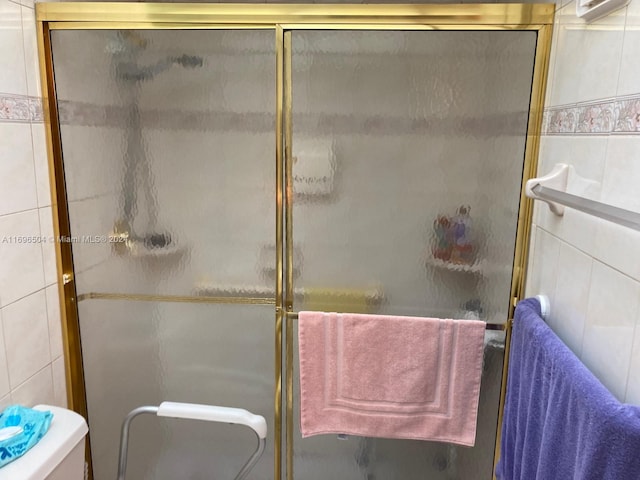 bathroom featuring an enclosed shower, toilet, and tile walls