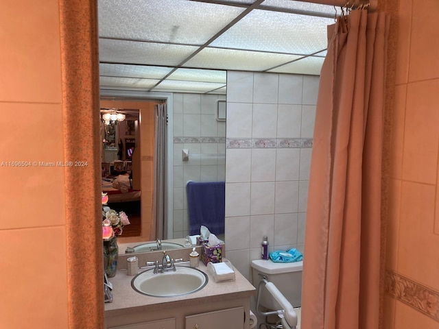 bathroom with ceiling fan, vanity, tile walls, and toilet