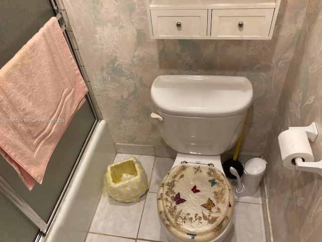 bathroom featuring tile patterned flooring, toilet, and enclosed tub / shower combo