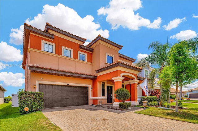 mediterranean / spanish home featuring a garage and a front yard