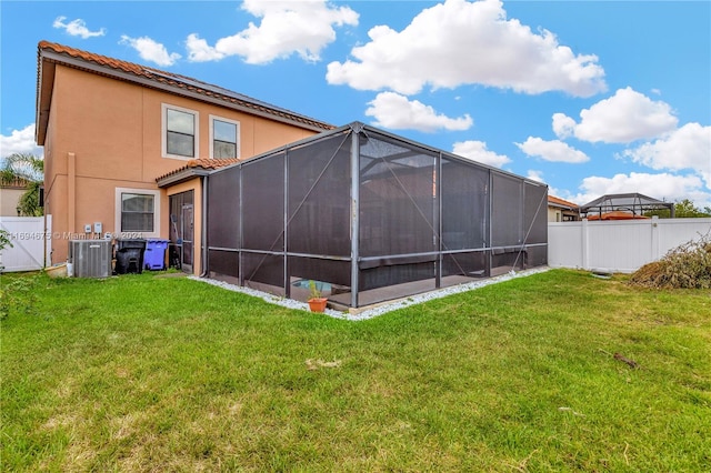 rear view of property featuring central air condition unit, a yard, and a lanai