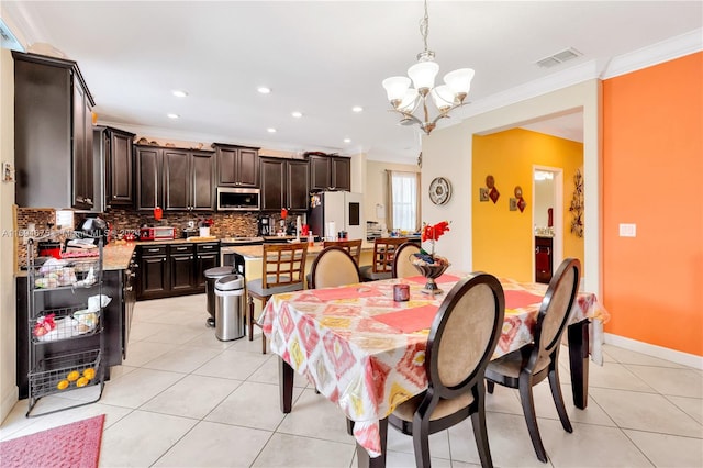 dining space with light tile patterned flooring, ornamental molding, and a chandelier