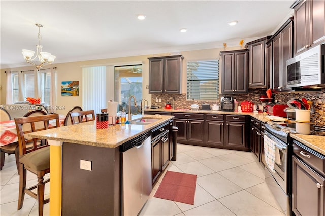 kitchen with sink, hanging light fixtures, stainless steel appliances, crown molding, and an island with sink