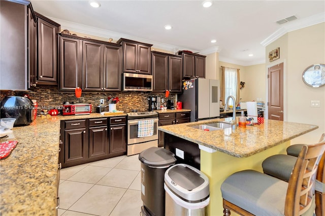 kitchen with light stone countertops, ornamental molding, appliances with stainless steel finishes, light tile patterned flooring, and a kitchen bar