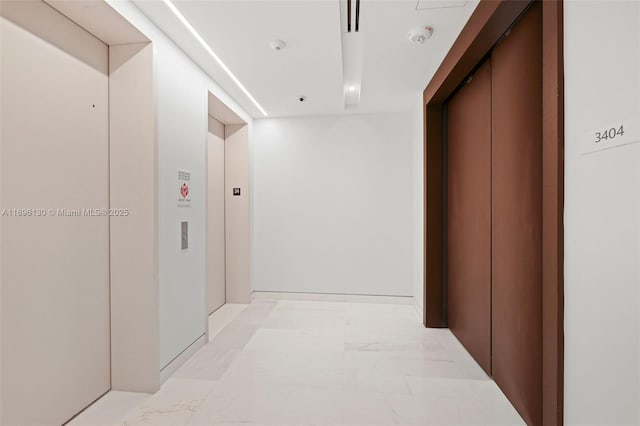 corridor featuring elevator and marble finish floor